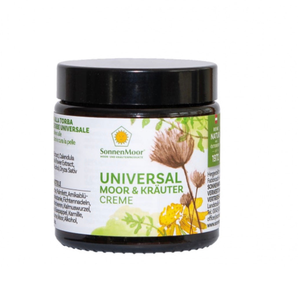 Tube SonnenMoor Naturprodukt Universal Moorcreme auf einem rustikalen Holzuntergrund, umgeben von Kräutern – die Creme wird zur intensiven Pflege und Beruhigung von Haut und Muskeln verwendet.